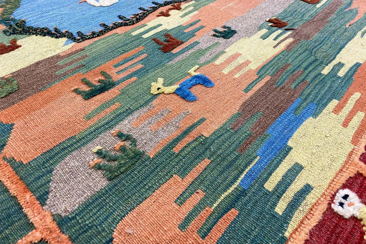 Close-up: Kilim with plant and animal motifs in blue, green, orange, and beige