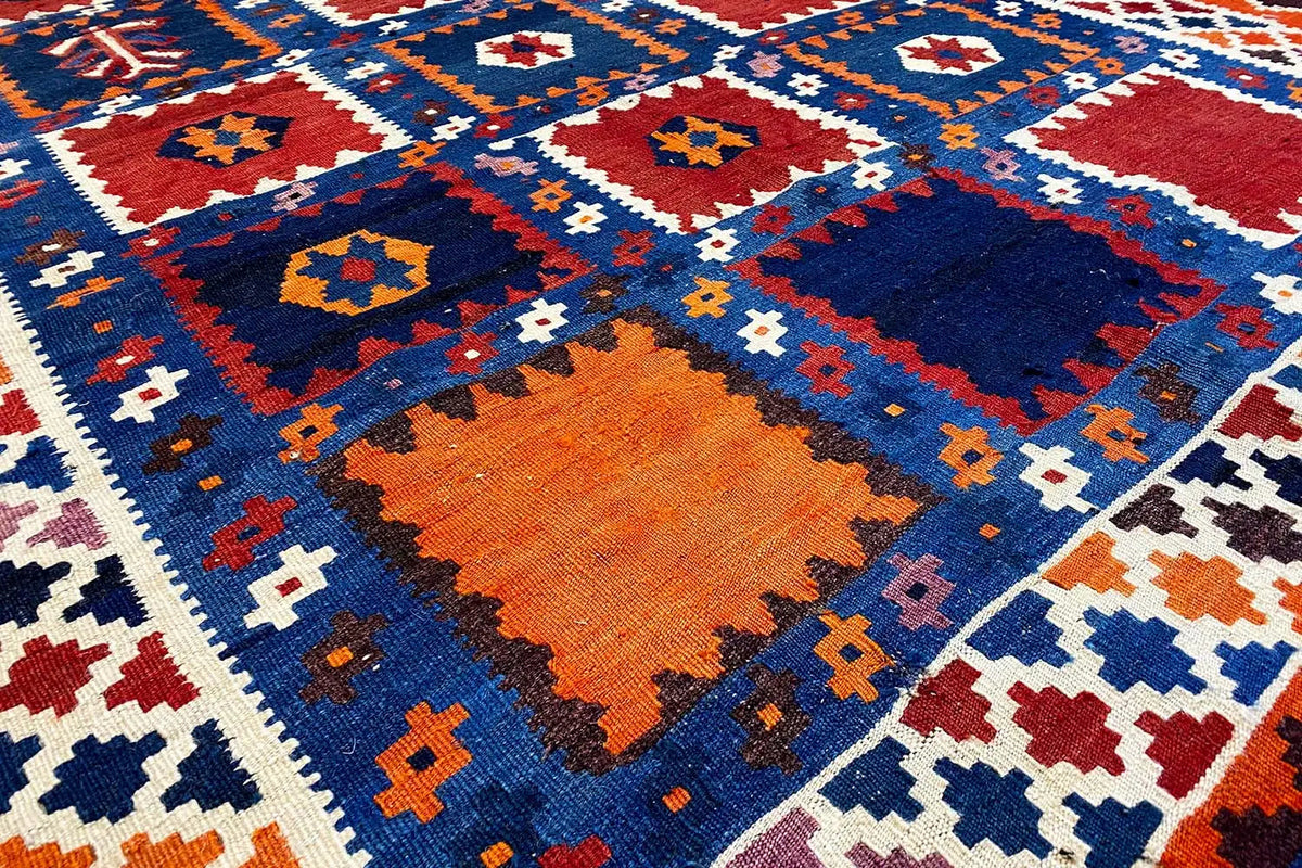 Kilim rug surface with cross and diamond motifs in blue, red, orange, and white.