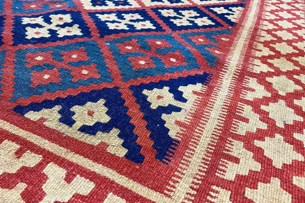 Kilim rug with geometric patterns in blue, red, and cream, close-up of the surface