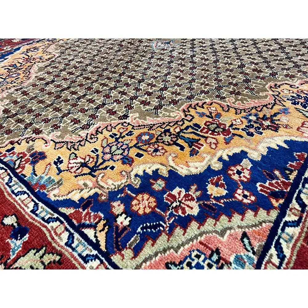 Hamadan rug with a dense geometric pattern in blue, red, and beige, close-up