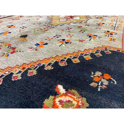 Rug with a dark blue base and colorful floral ornaments, with a border running around the edge