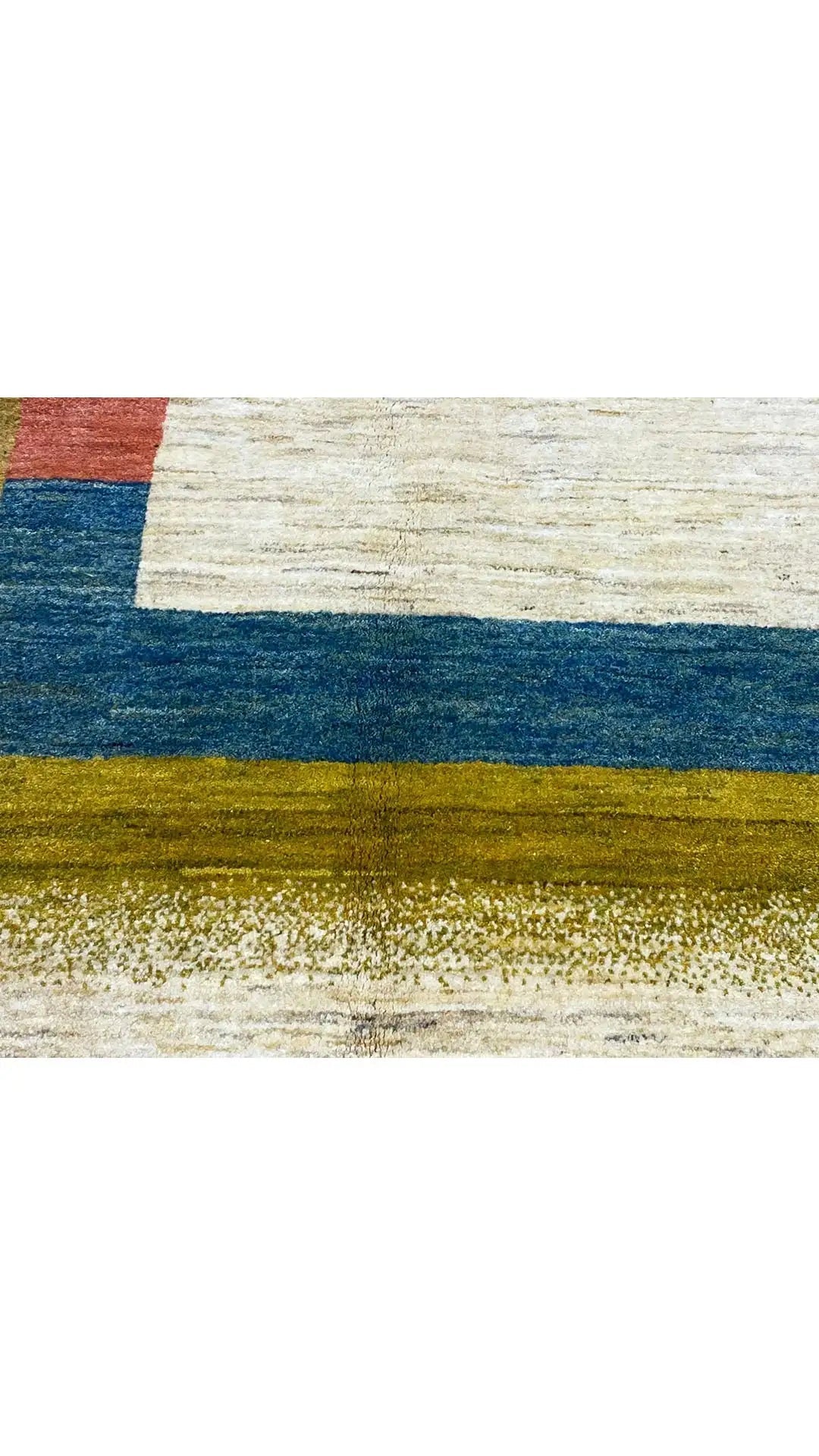 Gabbeh rug with an abstract striped pattern in blue, gold, and beige, right edge close-up.