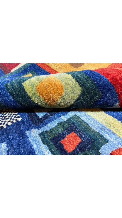 Gabbeh rug, close-up with geometric tile patterns in blue, red, yellow, and green.