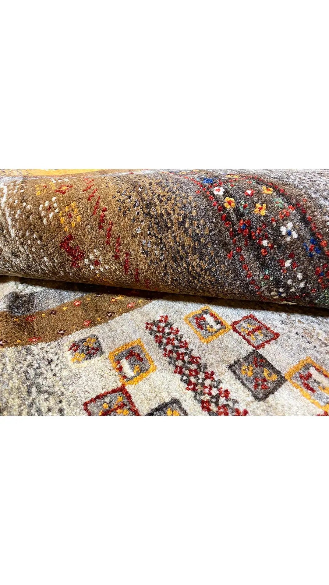 Rolled Gabbeh rug, intricate patterns in gray, beige, red, and yellow