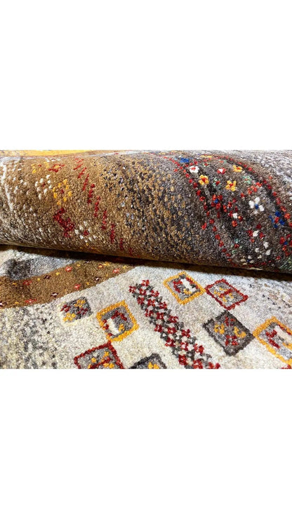 Rolled Gabbeh rug, intricate patterns in gray, beige, red, and yellow