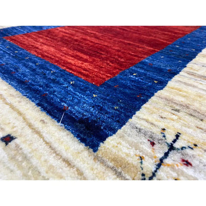 Gabbeh rug: close-up with a red triangle, blue fields, and a cream-colored border