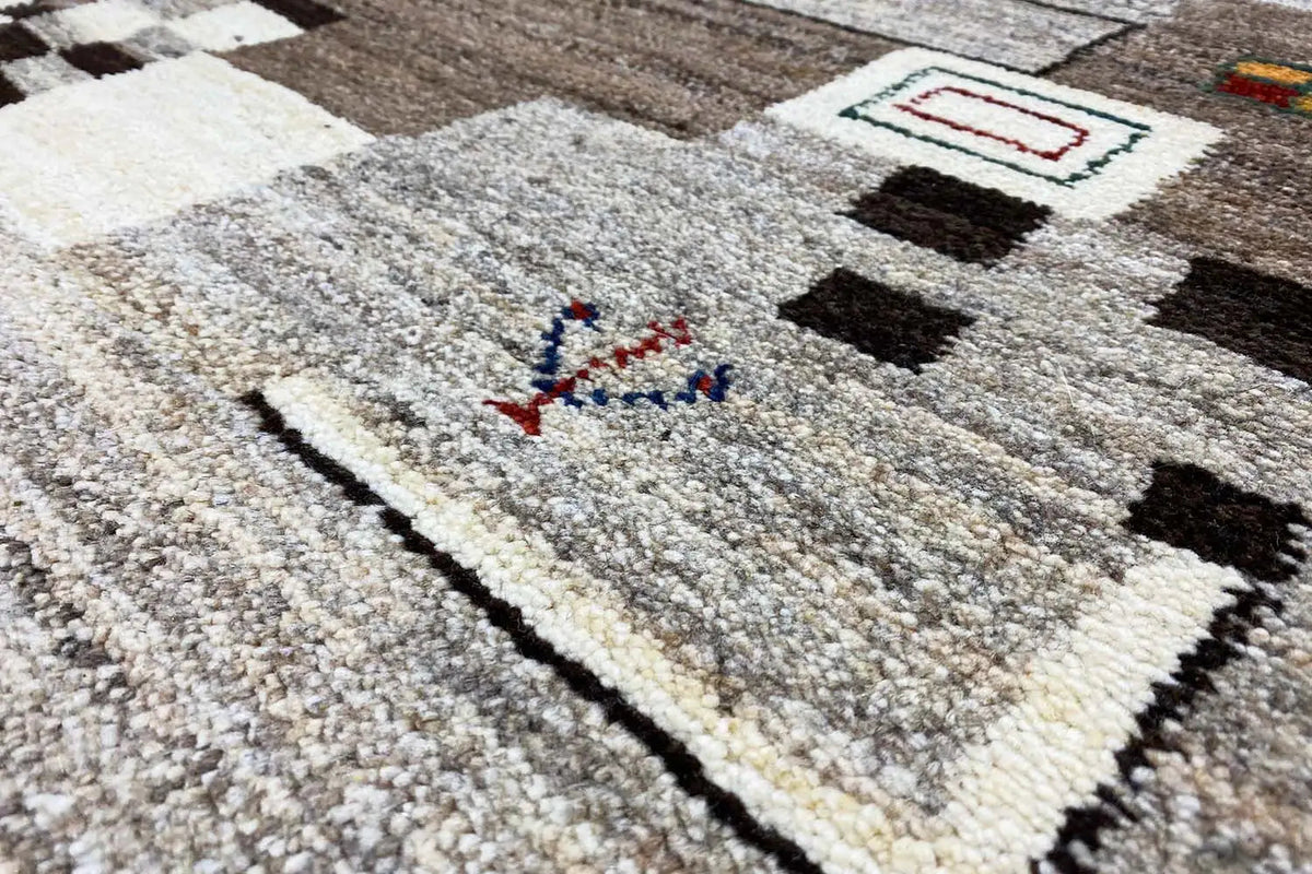 Gabbeh rug: light base pattern with geometric shapes, black border, close-up
