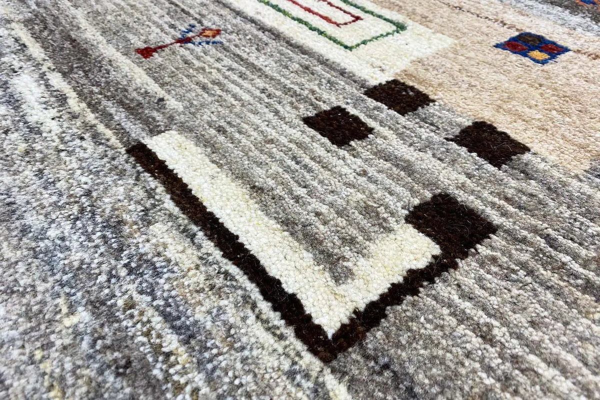 Gabbeh rug: close-up with gray pile and geometric squares in black and cream.