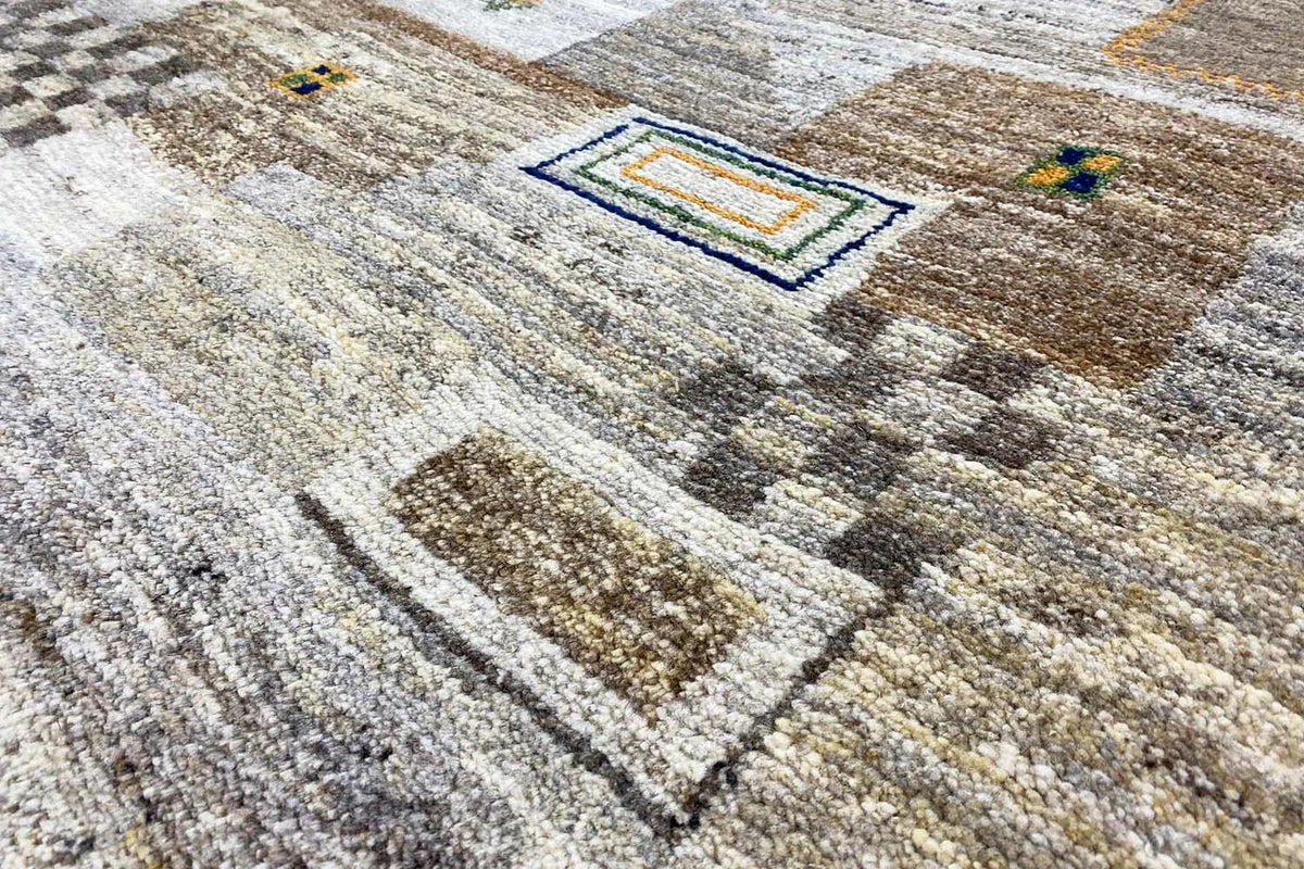 Gabbeh rug with a geometric pattern of beige and light gray areas, partly blue and brown