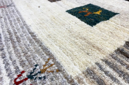 Gabbeh rug: cream-colored surface with gray stripes and a dark corner pattern