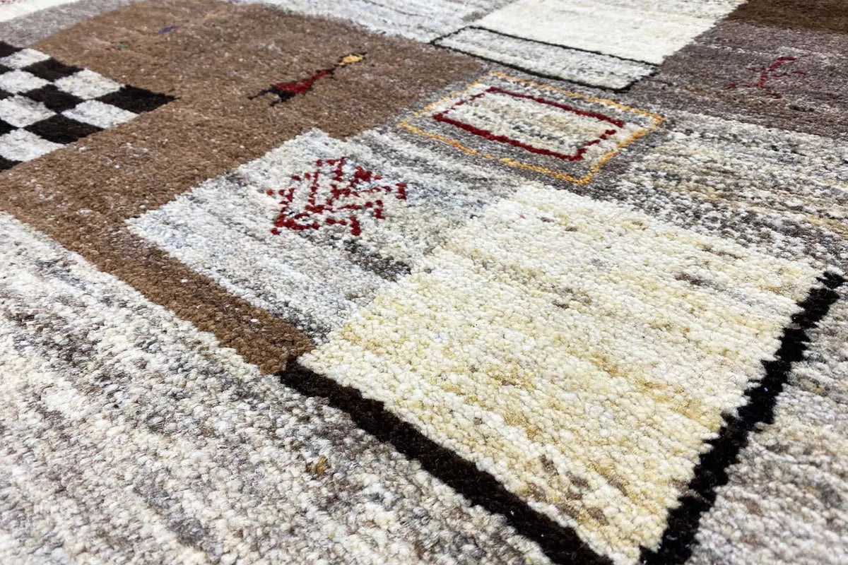 Gabbeh rug with a brown-and-white pattern and colorful accents, short pile, black border