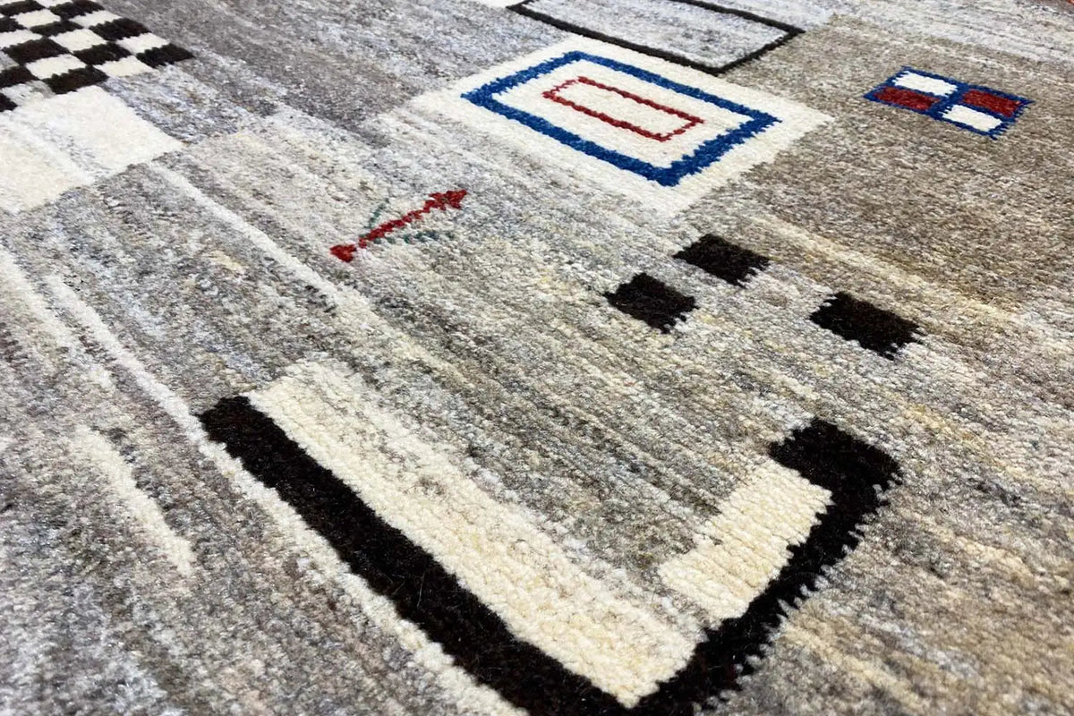 Gabbeh rug in detail: mottled gray, geometric patterns in black, cream, and blue