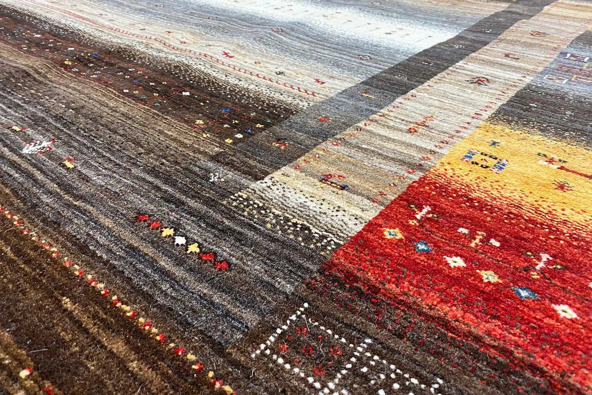 Gabbeh rug with multicolored ornamental stripes and deep brown in close-up.
