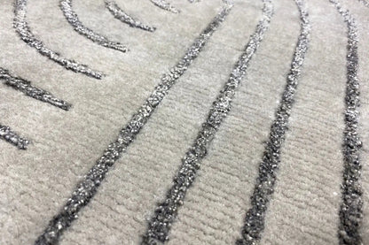 Close-up of a rug: gray pile with dark lines and mottled decorative edges