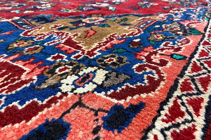 Oriental rug with a red background and blue-and-gold ornaments, close-up detail of the border