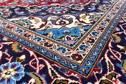 Keshan rug with an ornamental pattern in red, blue, and cream, close-up of the border
