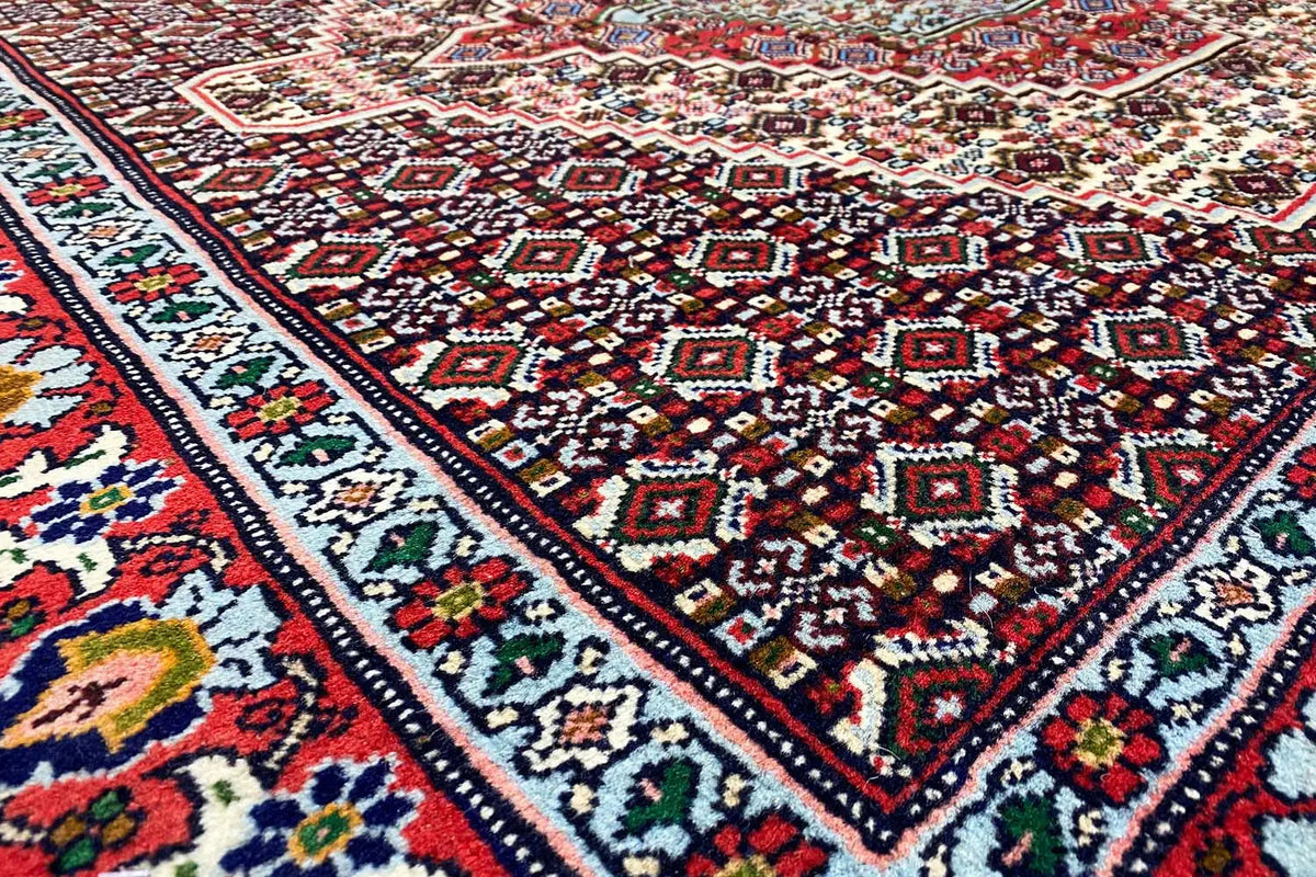 Hamadan rug with a red, blue, and cream ornamental pattern in the corner