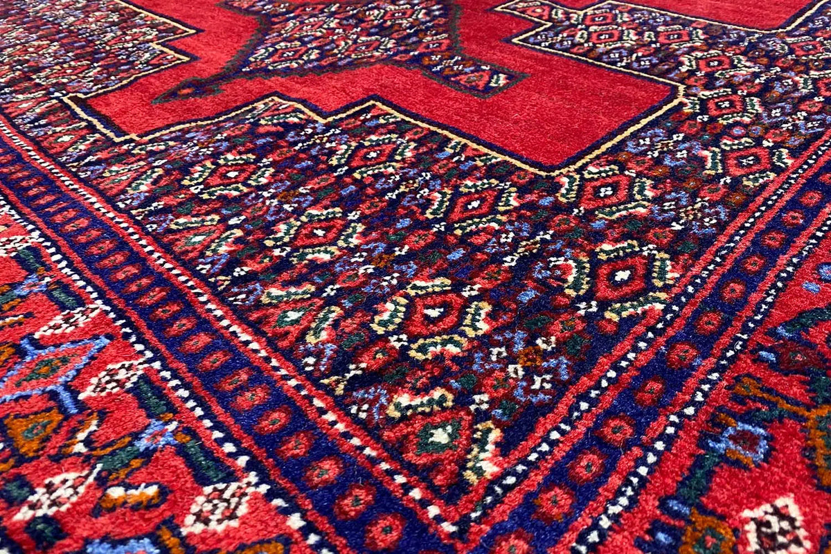 Hamadan rug with a red pattern and blue decorative lines, close-up view