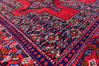 Hamadan rug with a red pattern and blue decorative lines, close-up view