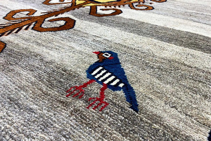 Close-up: blue and red bird embroidery on a beige Gabbeh rug with a light pile texture