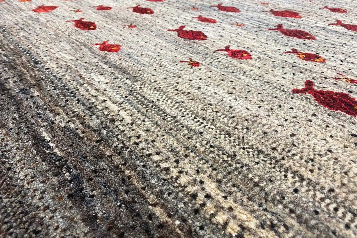 Gabbeh rug with a red pattern on a beige background, close-up of the pile texture