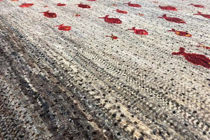 Gabbeh rug with a red pattern on a beige background, close-up of the pile texture