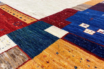Carpet detail with deep blue pile, red and yellow patchwork, and white accents