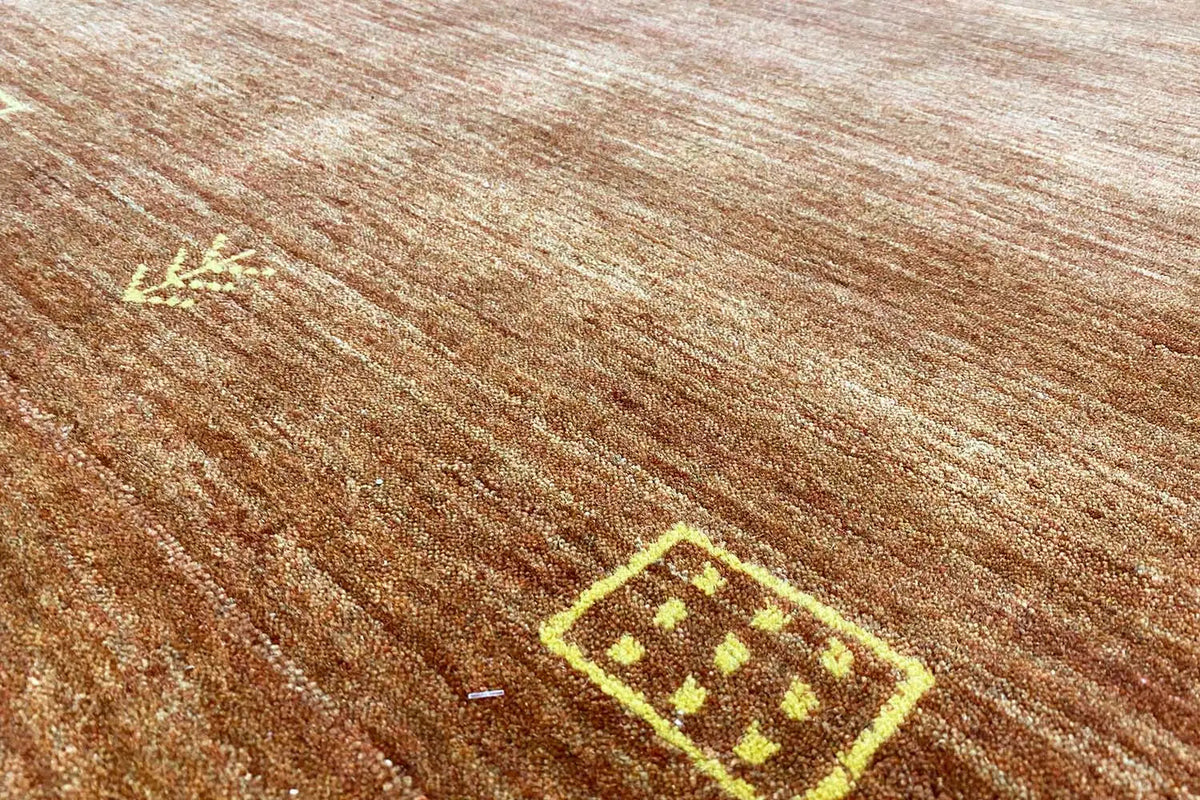 Close-up: woven carpet with gold decorative patterns and fine brown lines