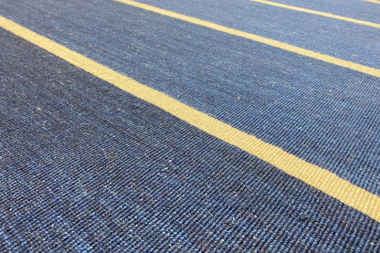 Close-up: dark blue kilim with fine texture lines and a yellowish-light stripe.
