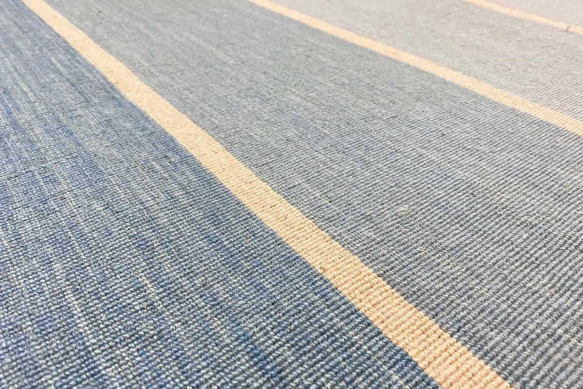 Close-up of a kilim rug: blue fabric with a beige striped pattern