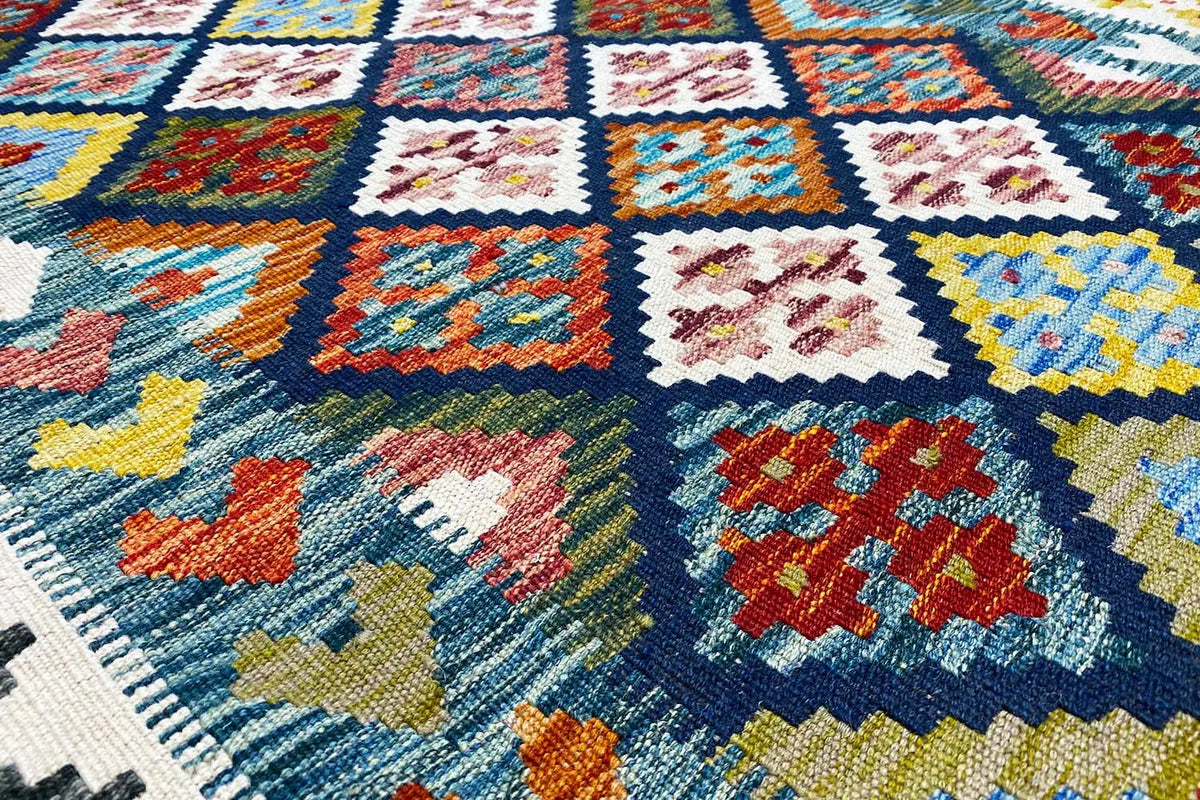 Close-up of a kilim rug: colorful squares, diamonds, and ornaments on a light background