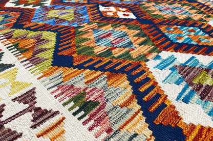 Kilim rug detail with colorful embroidered patterns, a white background, and fringes