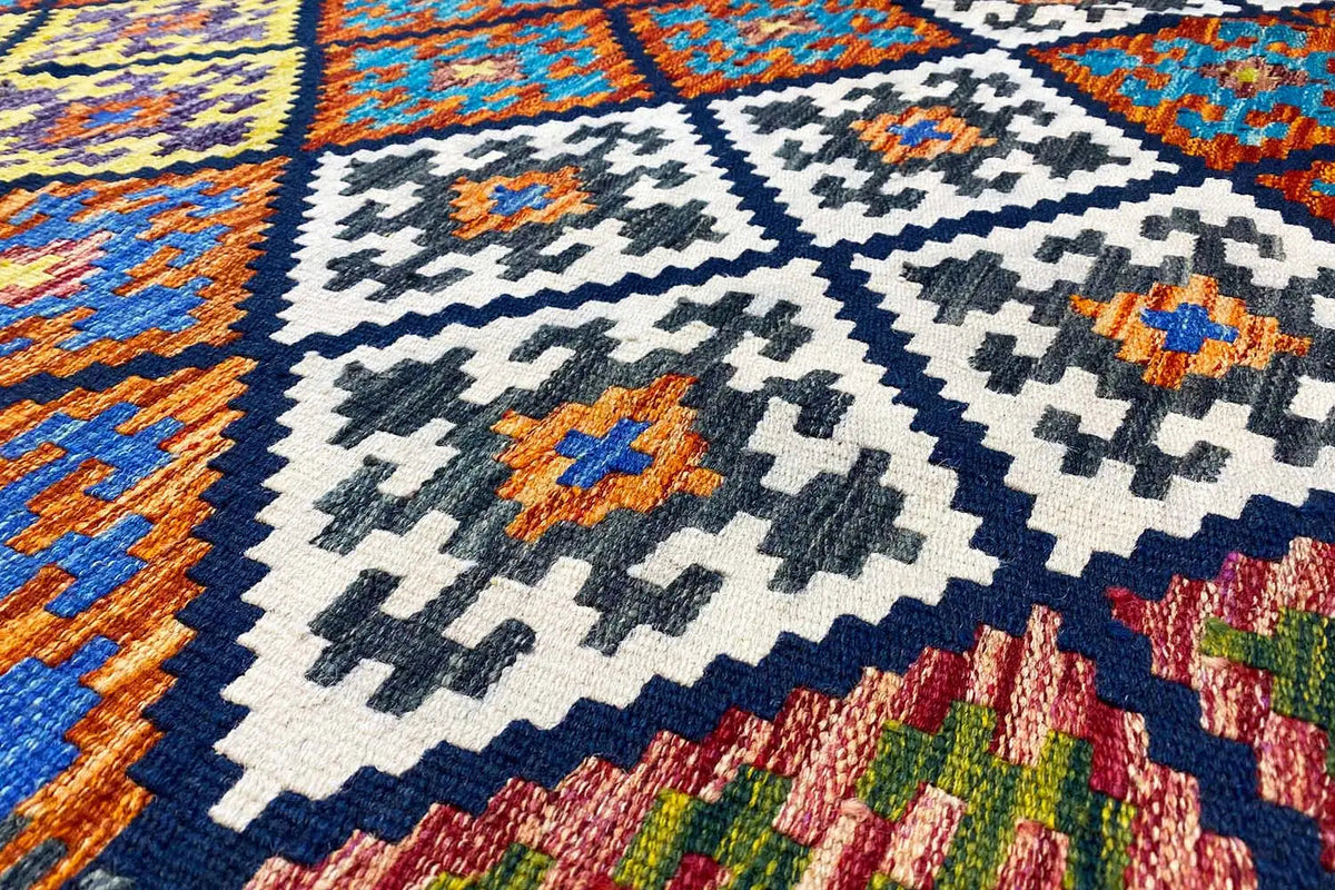 Kilim rug with a geometric pattern, close-up in blue, white, and orange.