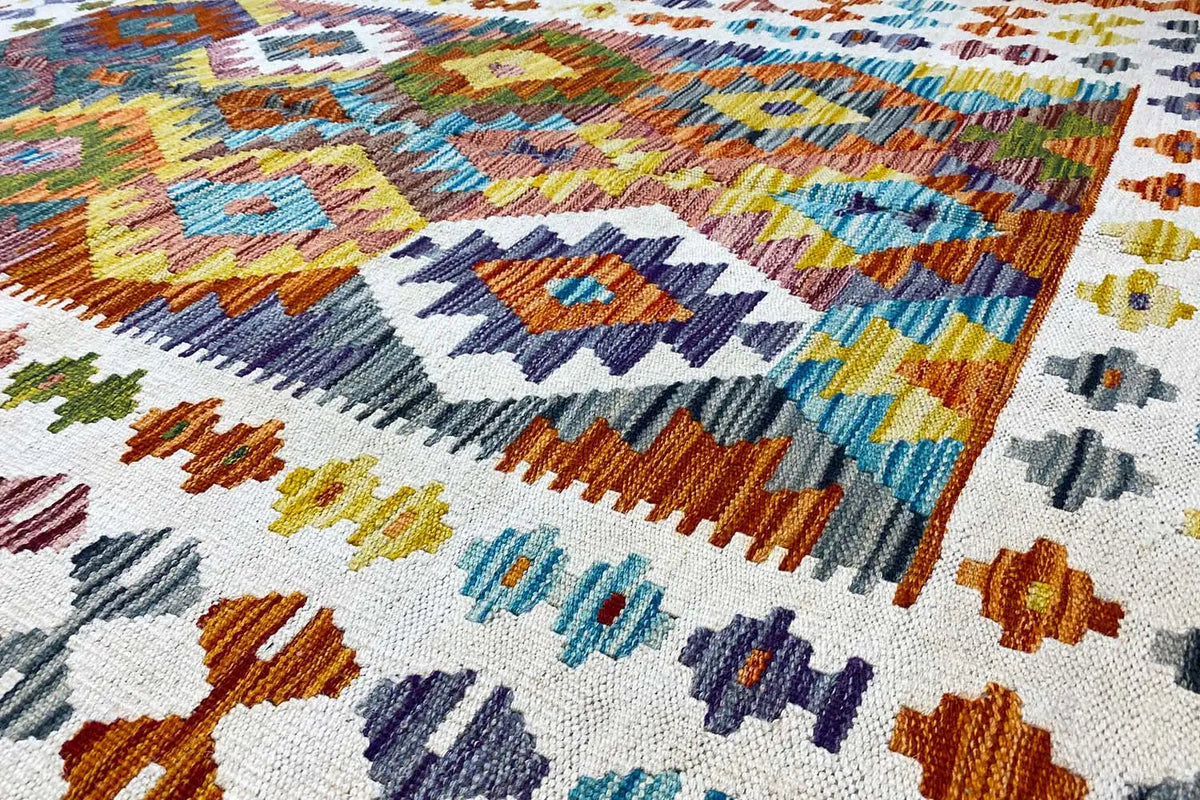 Afghan kilim with a geometric pattern in blue, orange, green, and cream, close-up