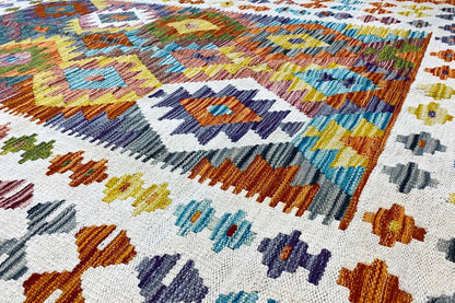 Afghan kilim with a geometric pattern in blue, orange, green, and cream, close-up