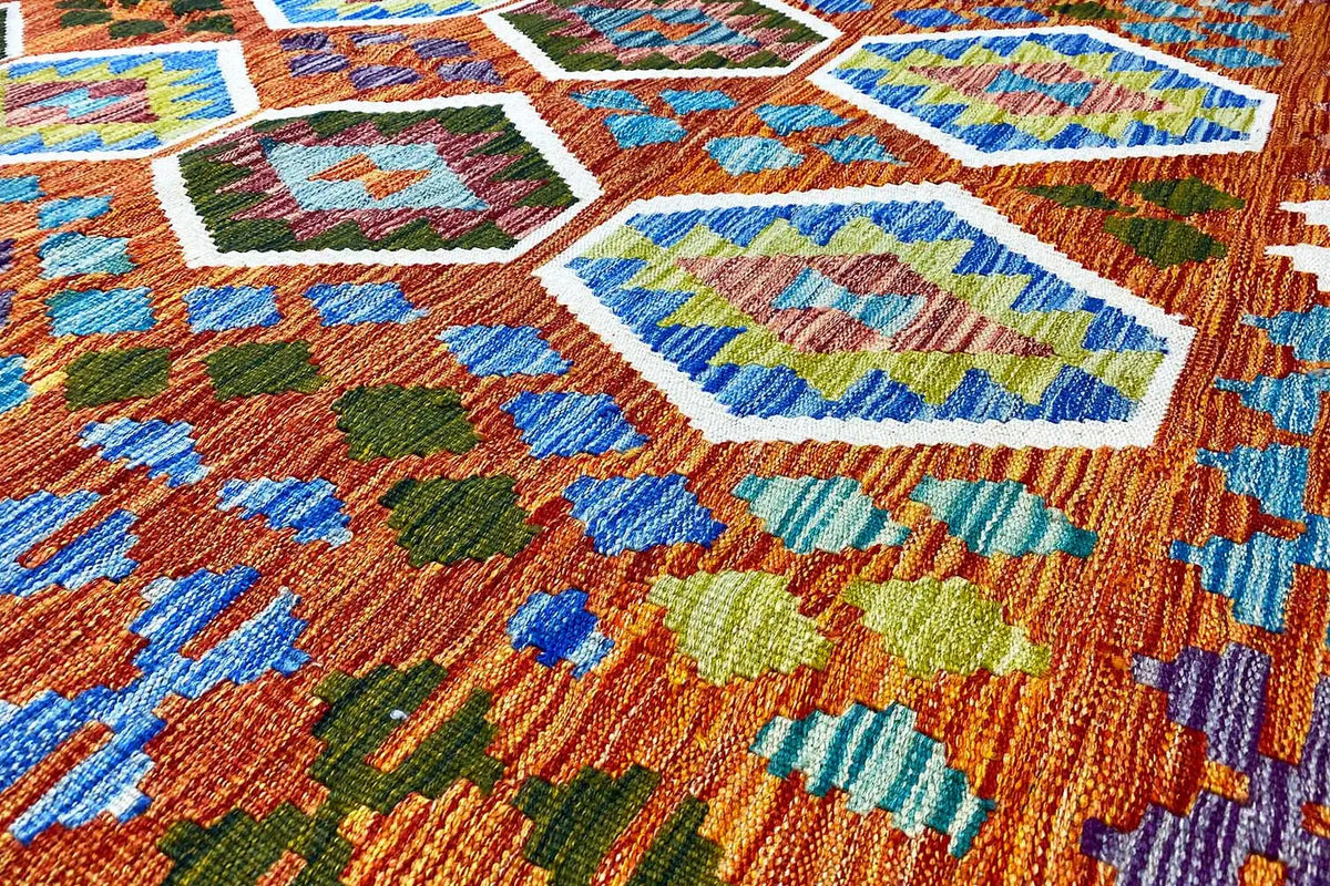 Colorfully patterned kilim with woven diamond, floral, and ornamental motifs in orange and blue