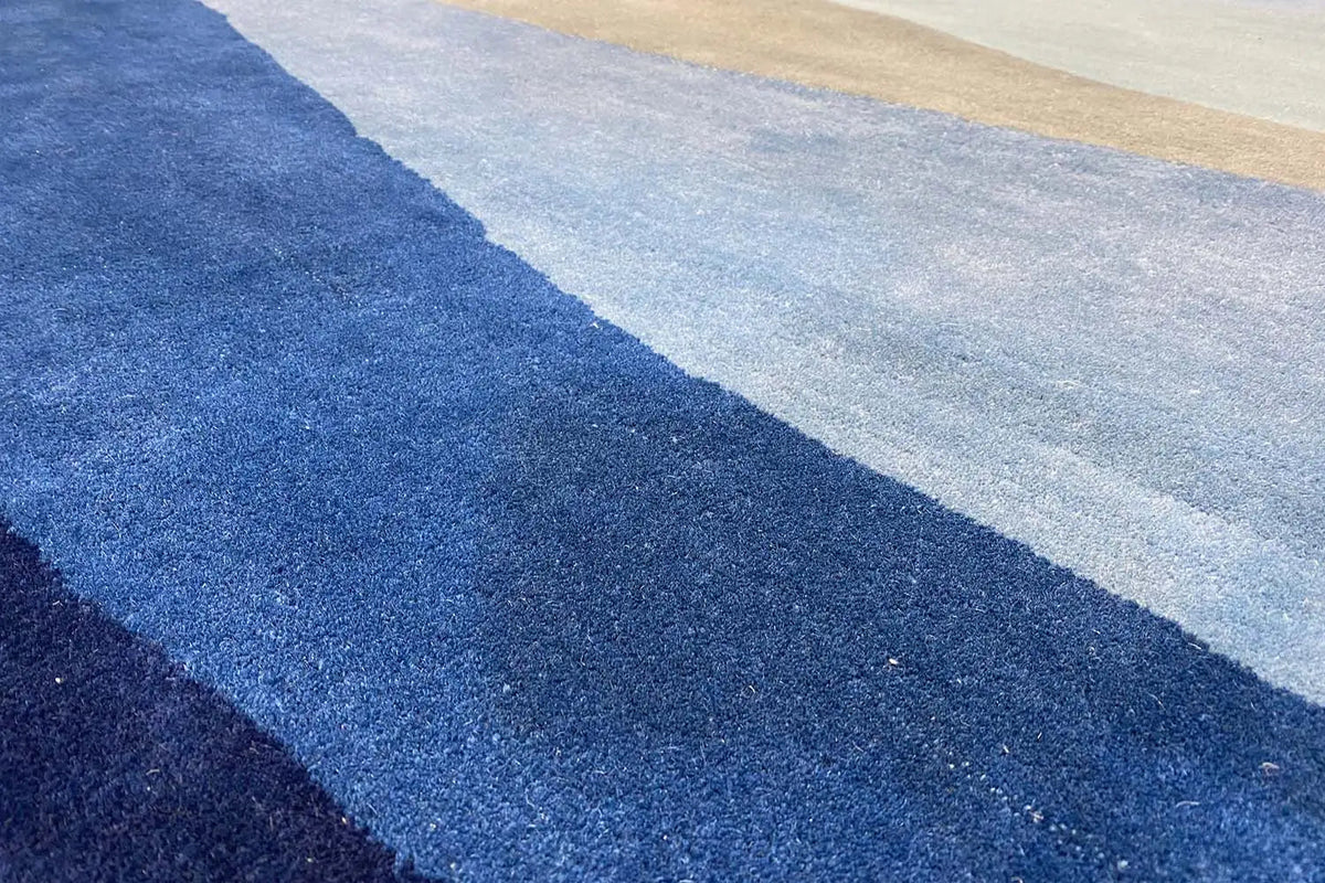 Blue hand-tufted rug with diagonal stripes, close-up of the pile texture