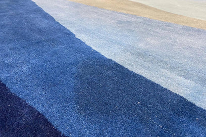 Blue hand-tufted rug with diagonal stripes, close-up of the pile texture