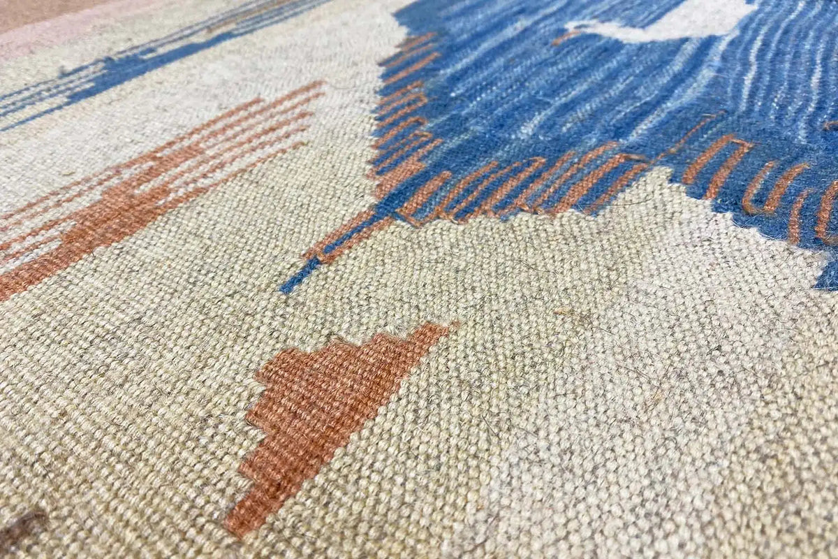 Kilim rug close-up: light texture with blue zigzags and earth-toned accents