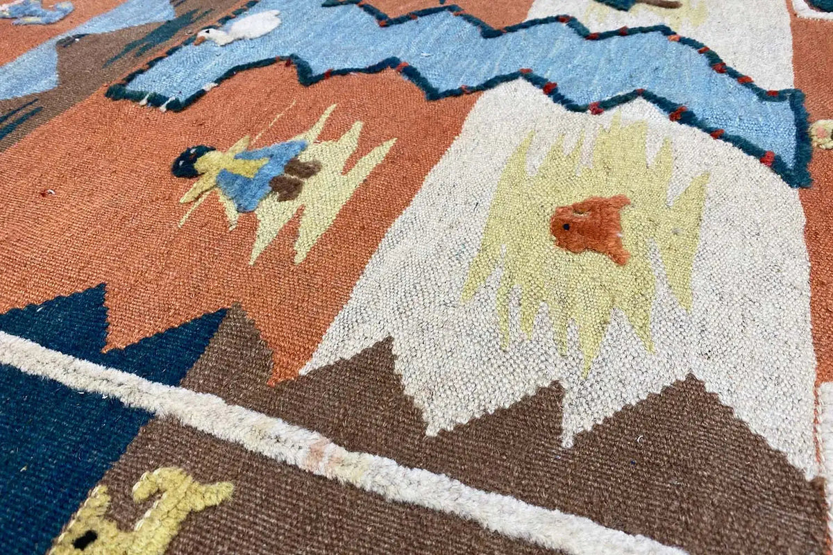 Kilim rug detail with floral motifs and zigzags in brown, blue, and cream