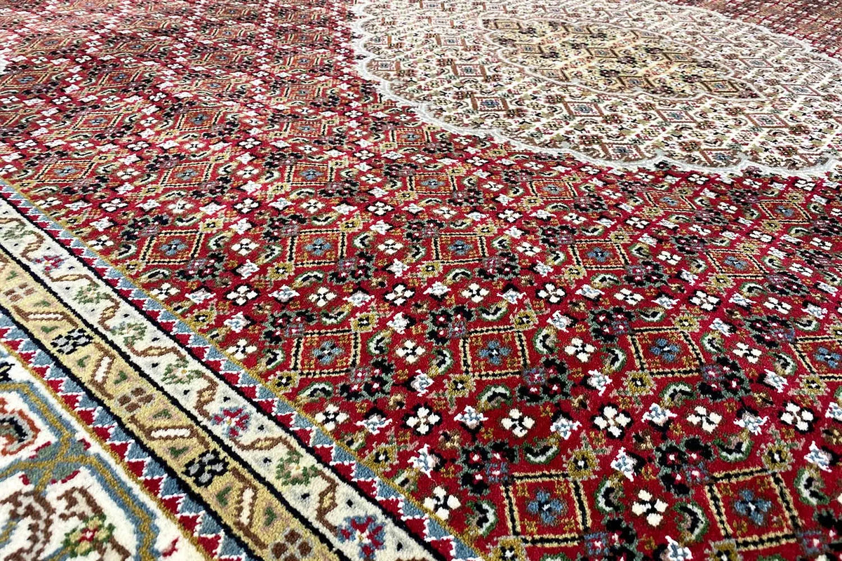 Rug with a red and green medallion, beige ornamentation, and a colorful border.