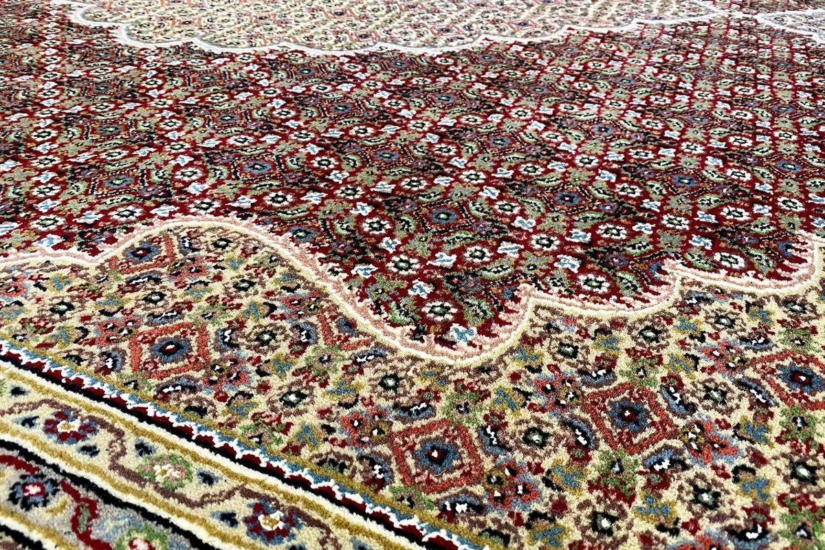 Carpet with a delicate ornamental pattern in red, green, and cream, close-up of the surface