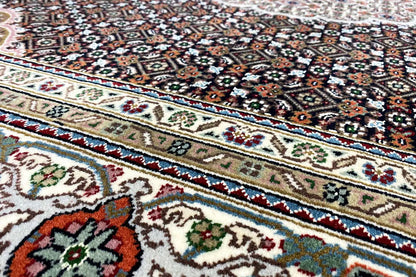 Tabriz-style rug with a multicolored ornamental and border pattern, close-up