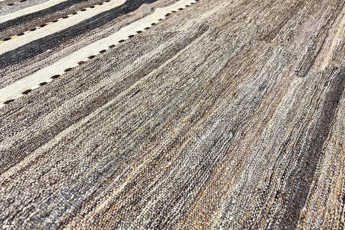 Rug with a striped pattern in gray, brown, and beige, with a visible fiber texture.
