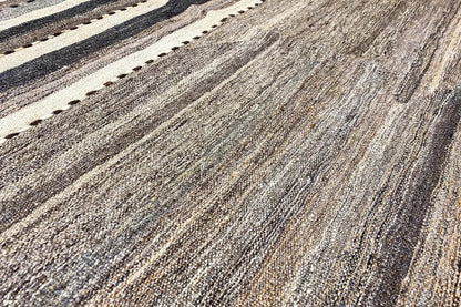 Rug with a striped pattern in gray, brown, and beige, with a visible fiber texture.