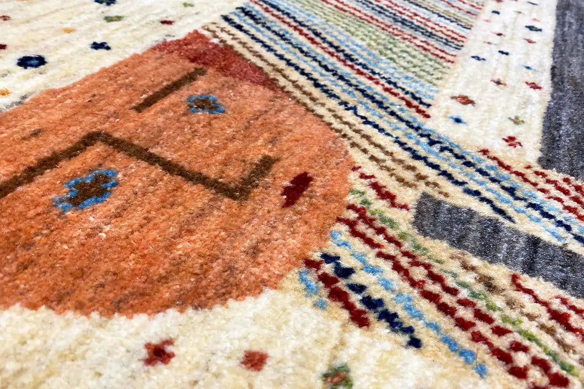 Close-up of a Gabbeh-Lori rug: orange-brown motif, colorful stripes, and dotted ornaments