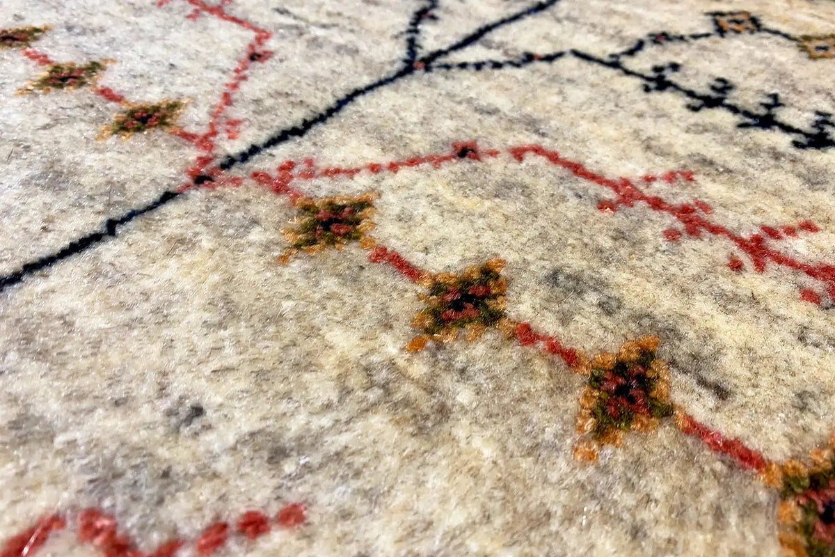 Gabbeh rug: beige wool pile with a red and black ornamental pattern, close-up
