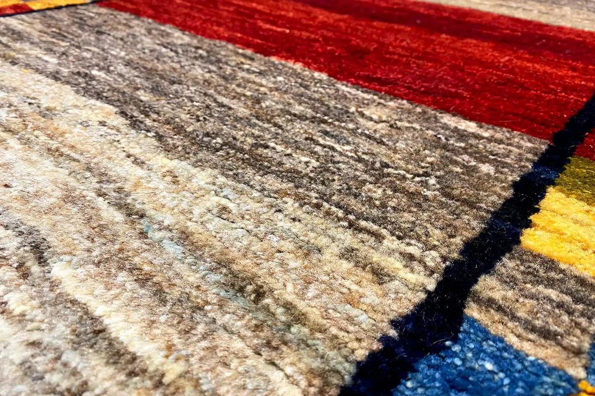 Gabbeh rug (190x83 cm), close-up: beige pile with a red border and blue-yellow stripes.