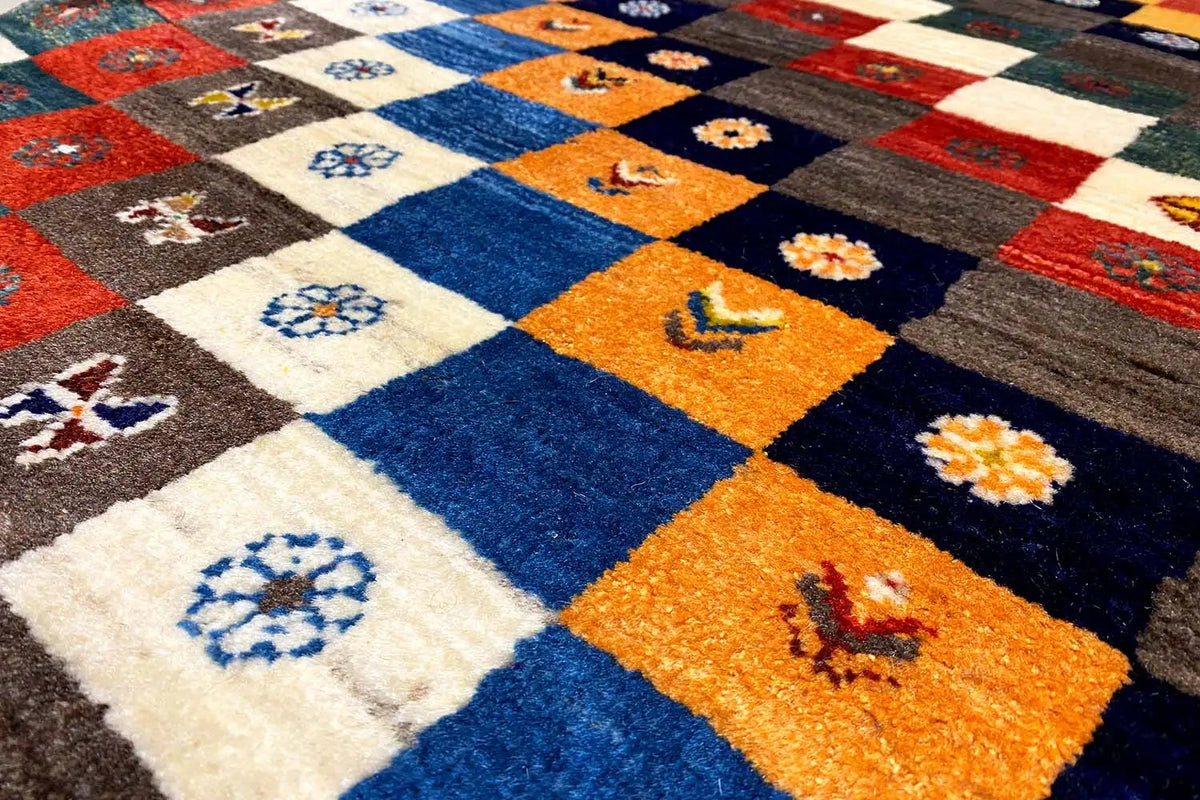 Gabbeh Lori rug with multicolored tile-look design and floral patterns in blue, orange, and cream
