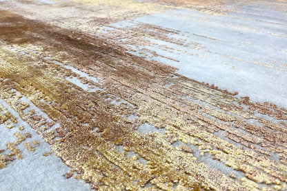 Rug detail: golden-brown lines and patterns on a light gray background